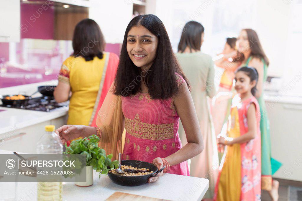 Portrait of Happy Indian teenage girl in kitchen holding cooking