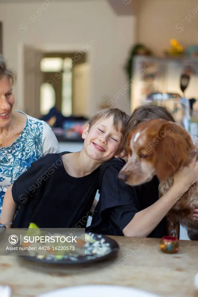 Happy family with dog eating lunch at dining table