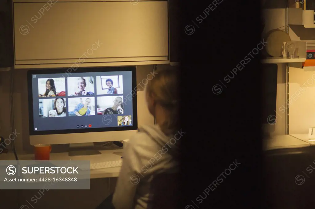 Woman video conferencing with colleagues at computer in home office