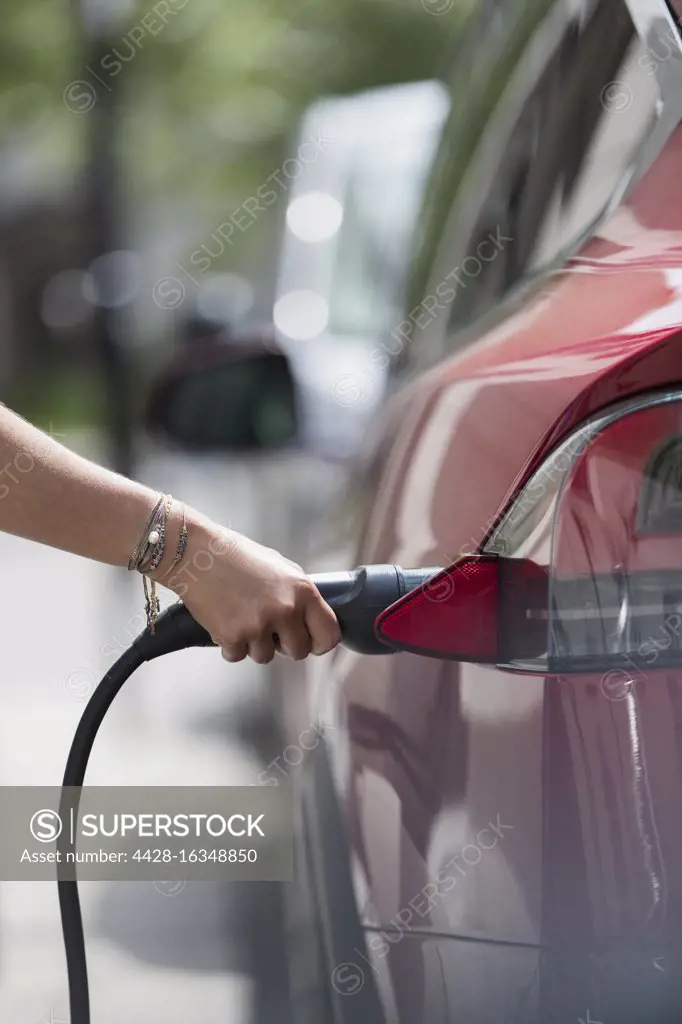 Woman recharging electric car