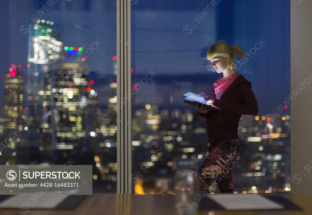 Businesswoman with digital tablet working late at highrise office