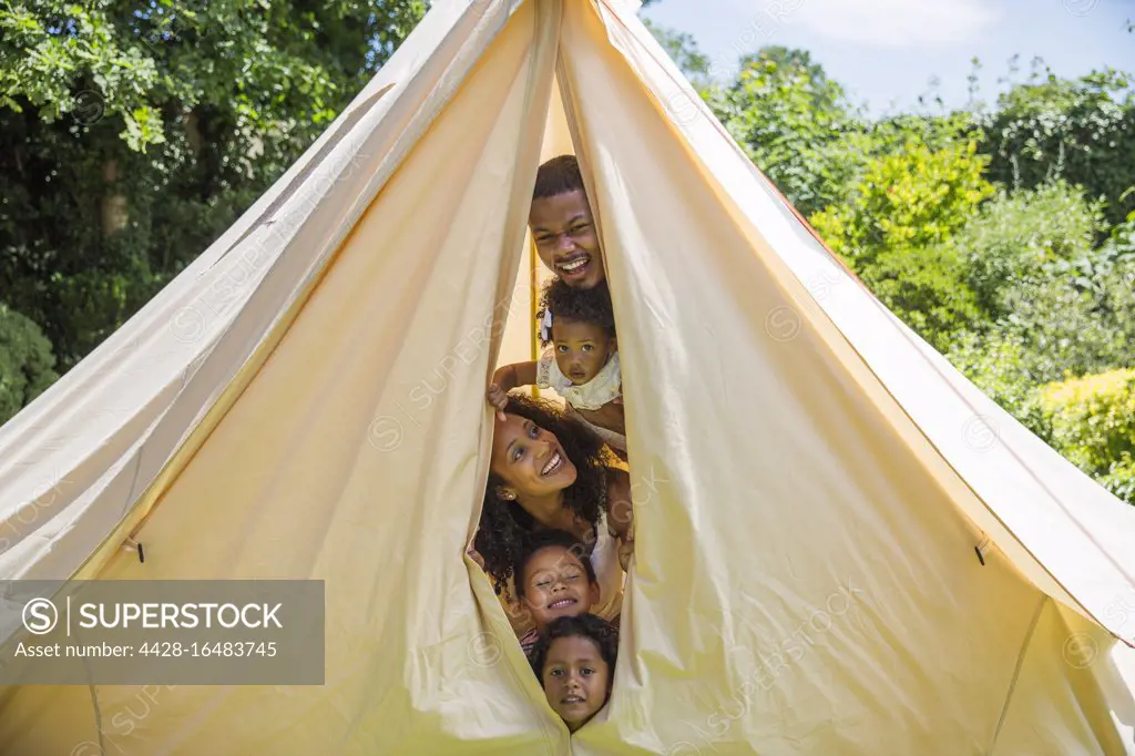 Portrait playful family peering from inside tent