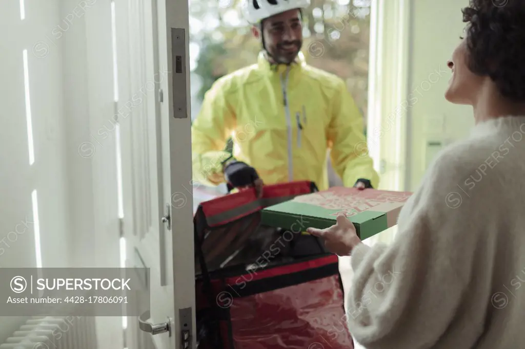 Woman receiving pizza from friendly delivery man at front door