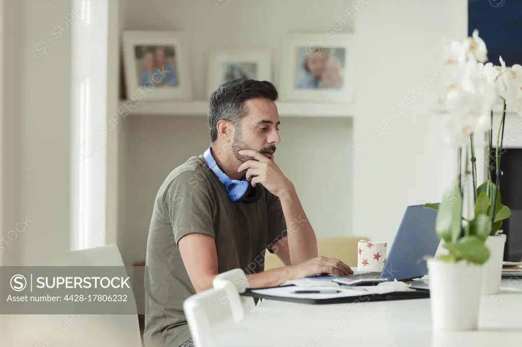 Man working from home at laptop on dining table