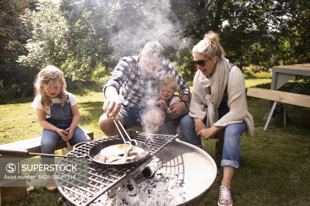 Happy family cooking breakfast on campsite grill