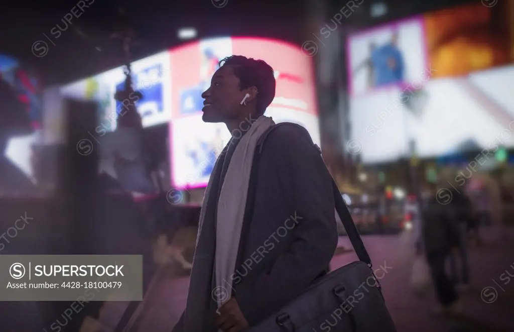 Young woman walking in Peccadillo Circus at night, London, UK