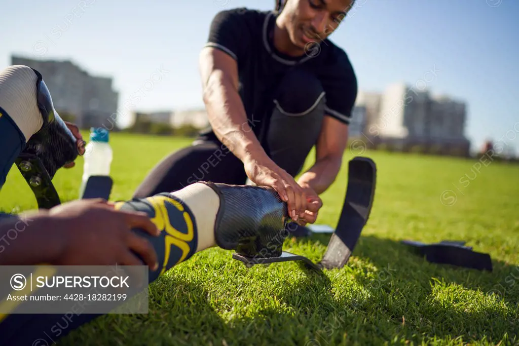 Coach helping amputee athlete with running blade prosthetic in park