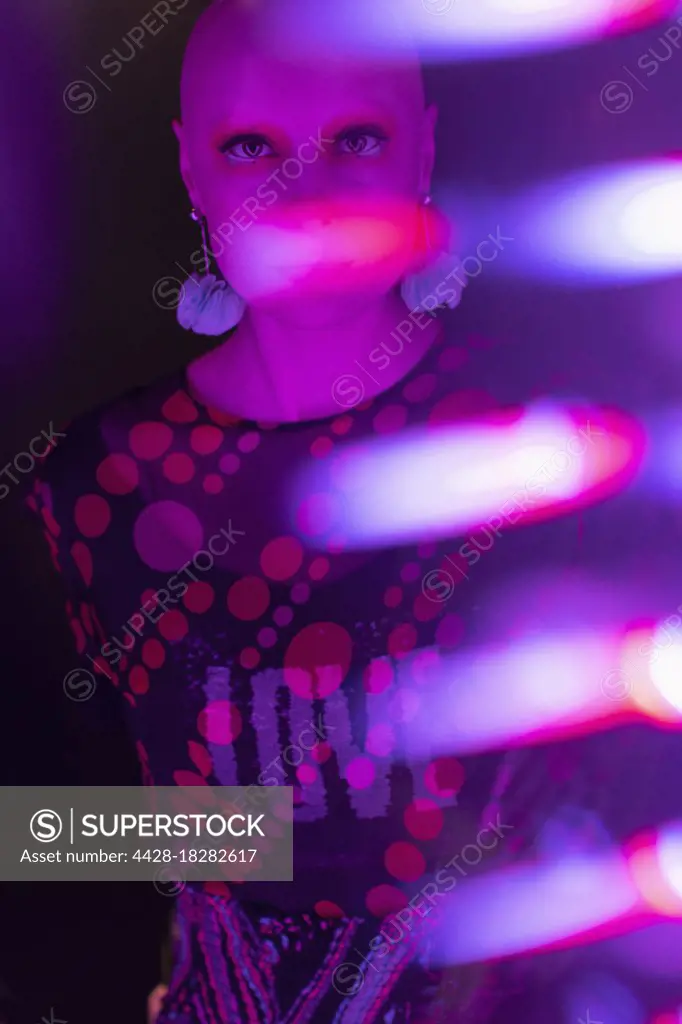 Portrait stylish woman with shaved head in neon light