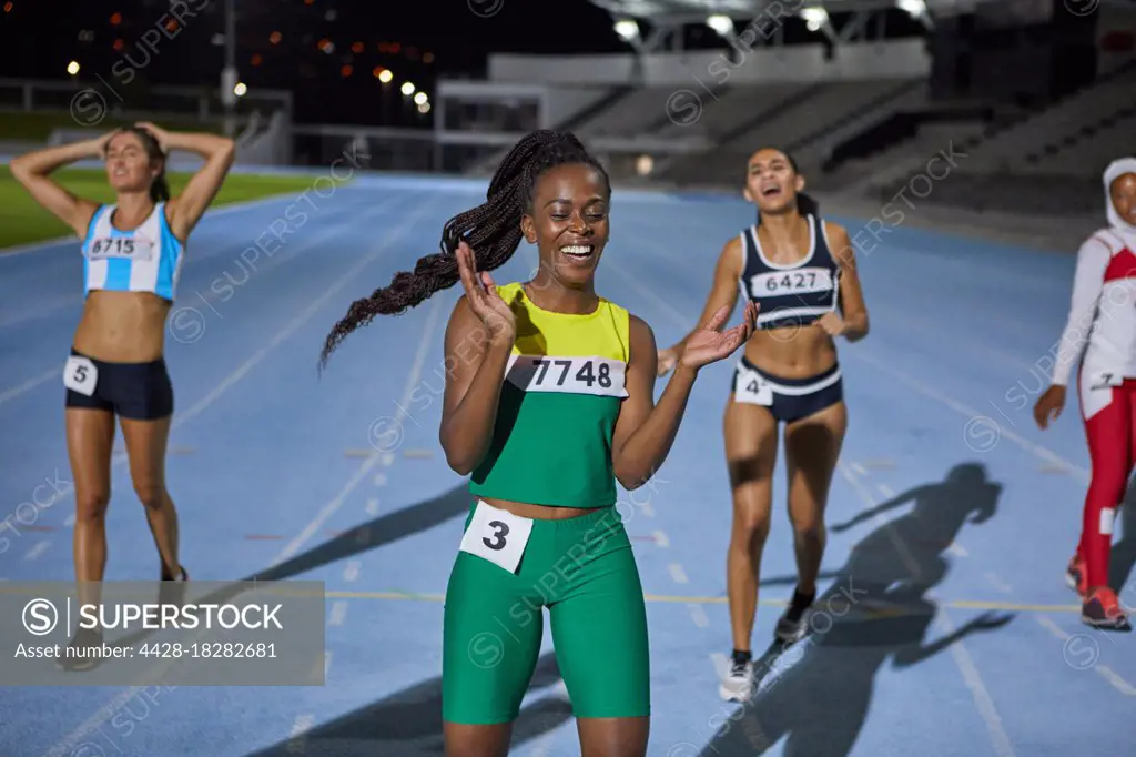 Happy female track and field athlete celebrating after race on track