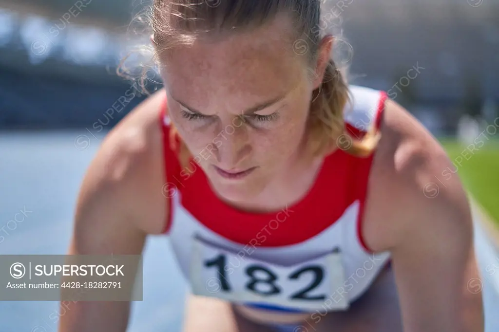 Close up focused female track and field athlete preparing for race