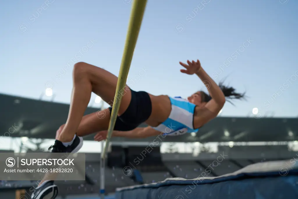 Female track and field athlete high jumping over pole