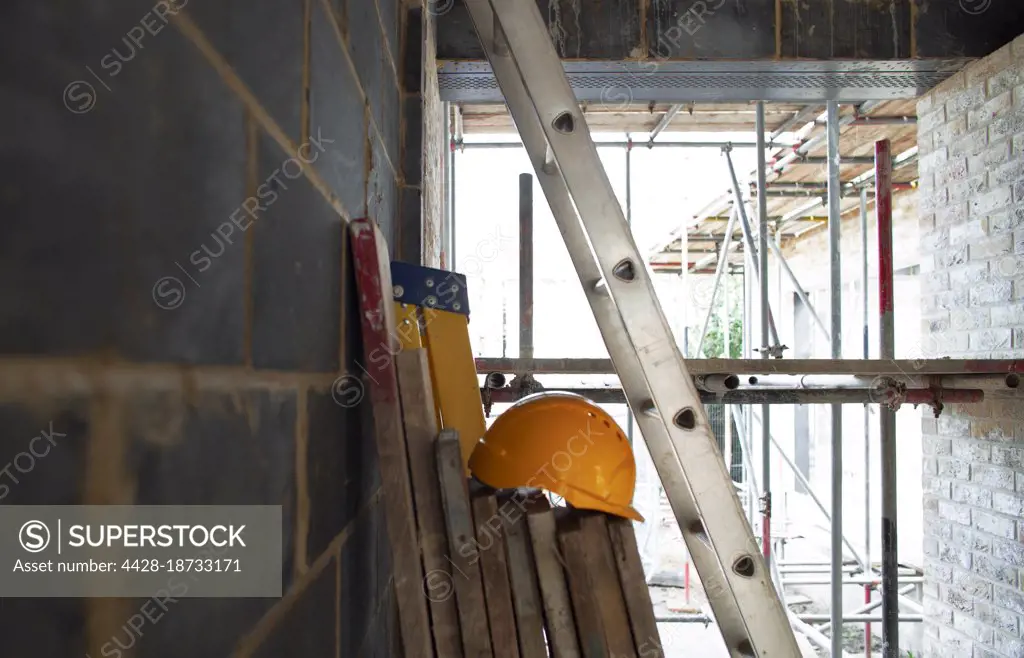 Hard hat, wood planks and ladders at construction site