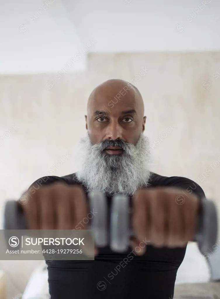 Focused senior man exercising with dumbbells