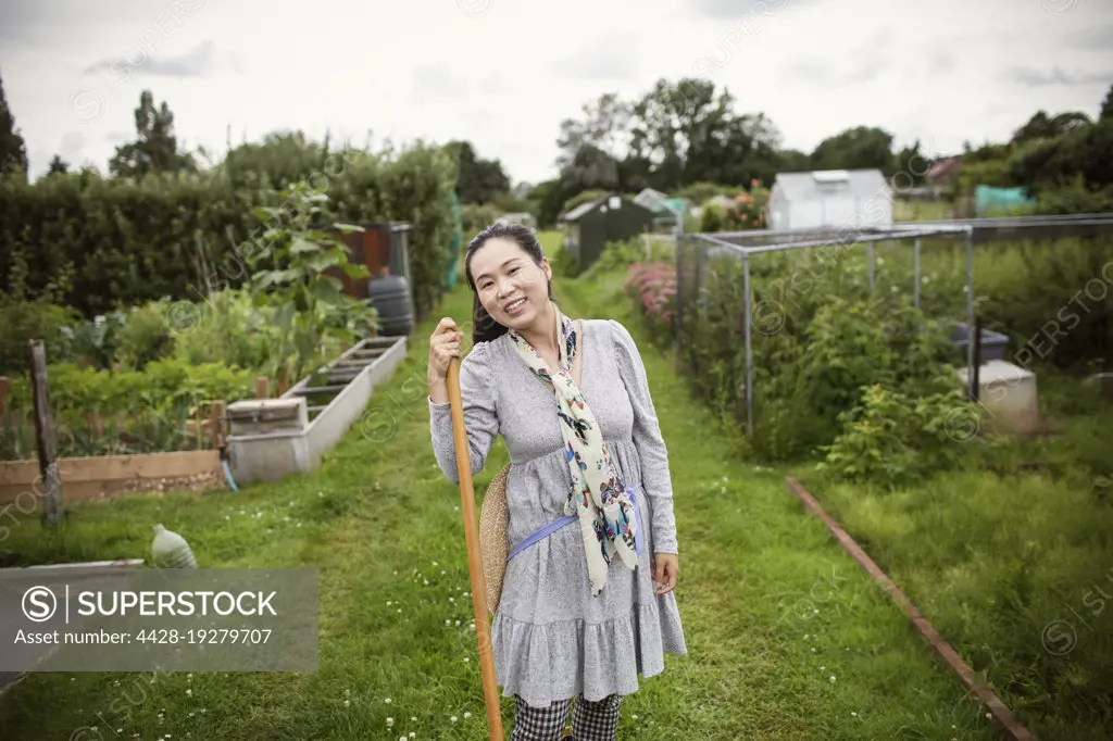 Portrait happy woman gardening in community vegetable garden