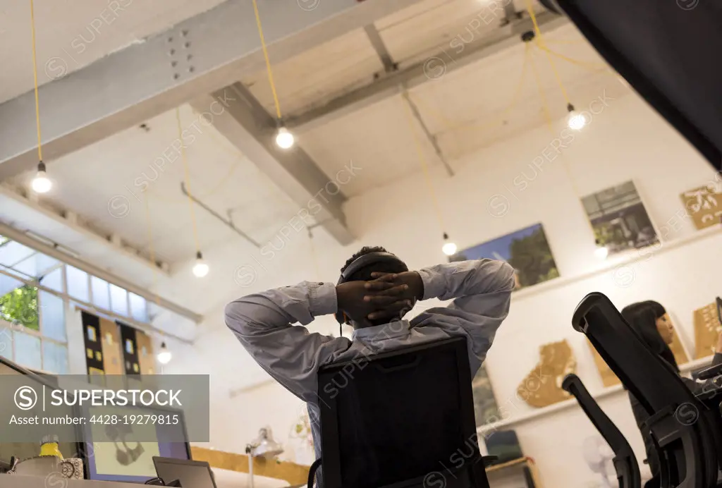 Businessman with hands behind head working in office