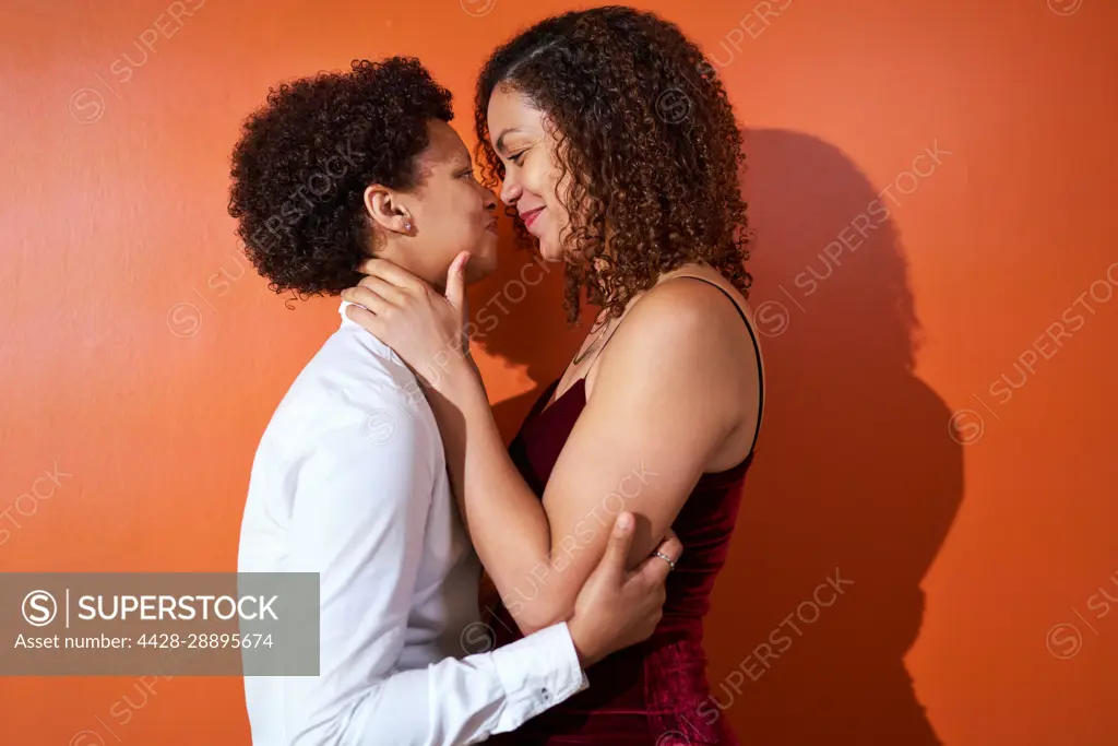 Portrait happy lesbian couple with curly hair smiling face to face