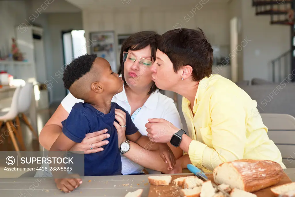 Lesbian couple and cute son puckering lips at dinner table