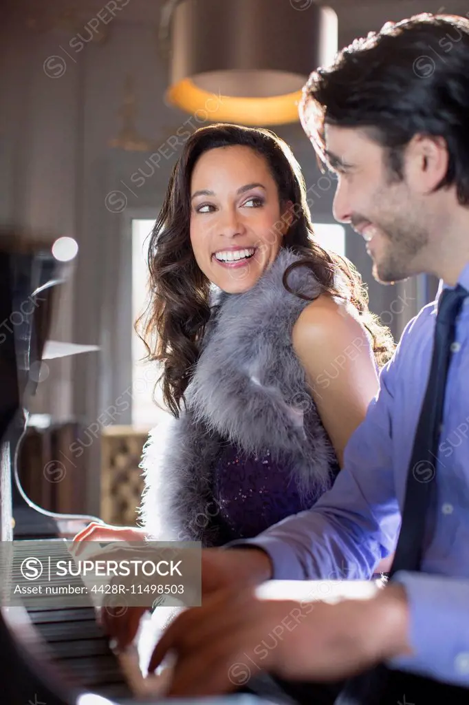 Close up of well dressed couple playing piano in lounge