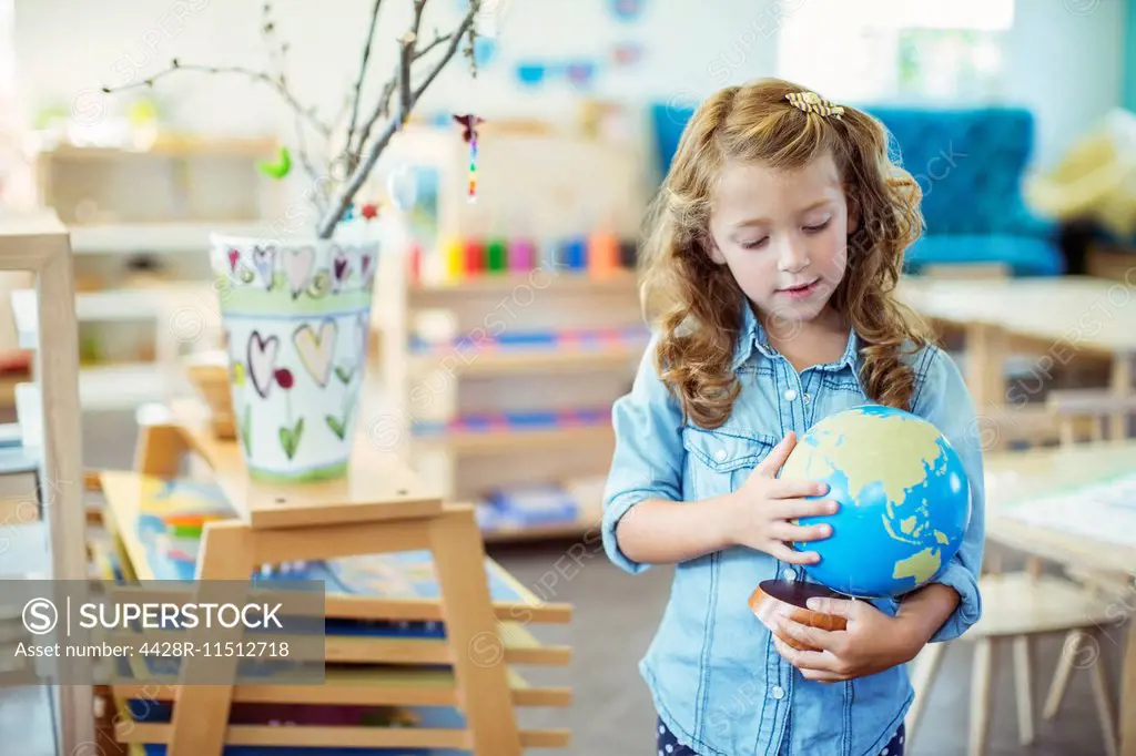 Student examining globe in classroom