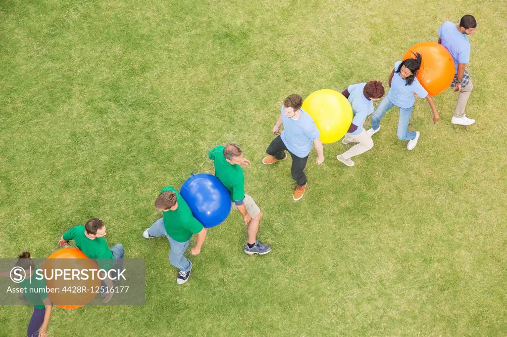 Teammates performing fitness ball team building activity