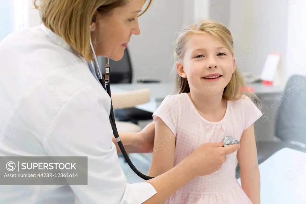 Pediatrician using stethoscope on girl patient in examination room