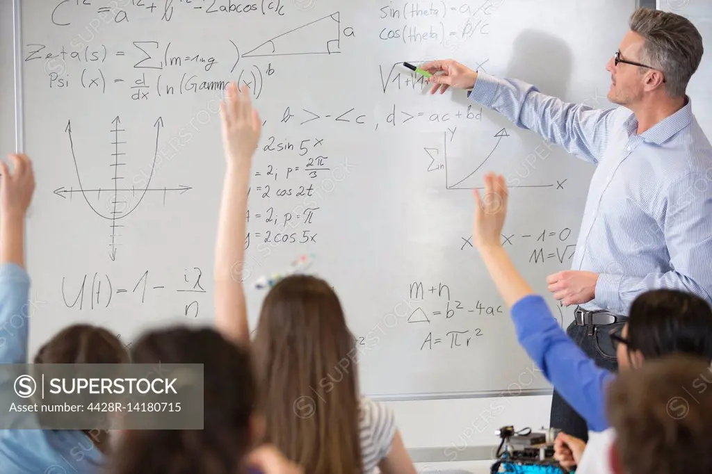 Male teacher leading physics lesson at whiteboard in classroom