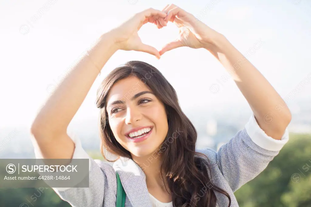 Woman making heart-shape with hands outdoors, Paris, France