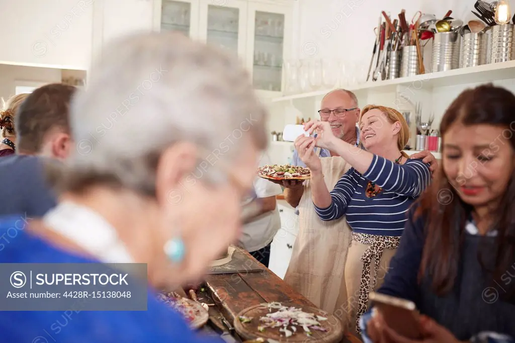 Senior couple taking selfie with pizza in cooking class