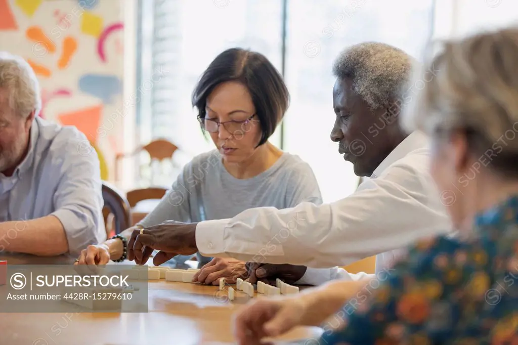 Senior friends playing mahjong at table in community center