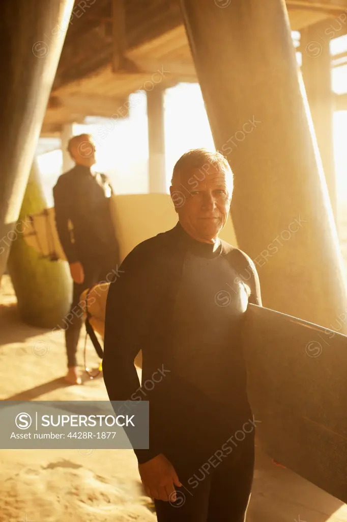 Los Angeles, USA, Older surfers carrying boards under pier