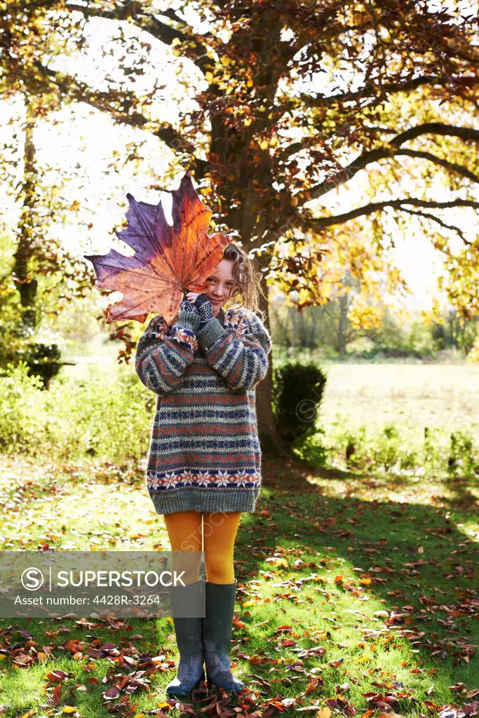 Girl playing with autumn leaf outdoors,belmonthouse, UK