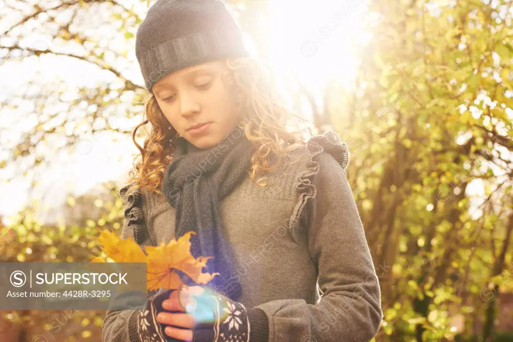 Girl carrying autumn leaf outdoors,belmonthouse, UK