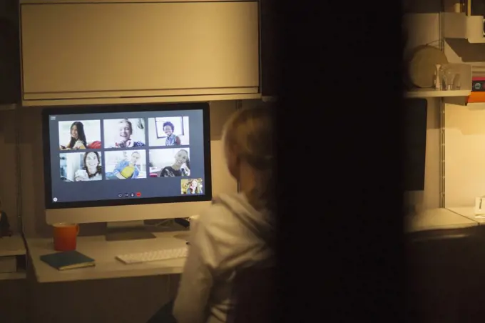 Woman video conferencing with colleagues at computer in home office