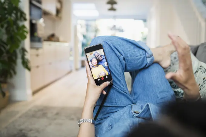 Woman on sofa video chatting with friends on smart phone screen