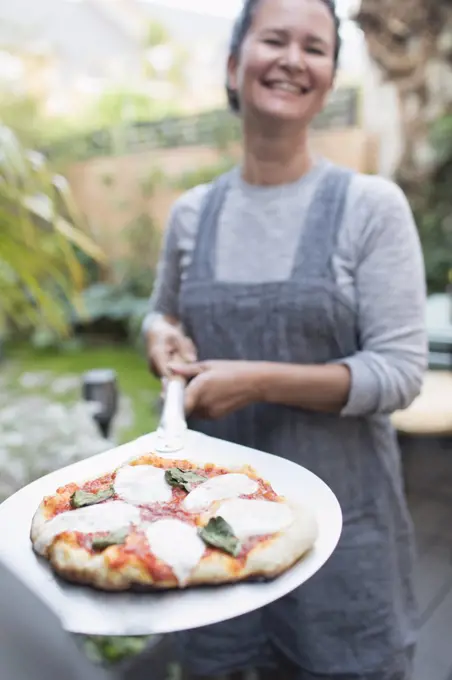Portrait happy woman cooking fresh homemade pizza outdoors