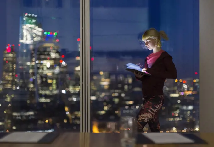 Businesswoman with digital tablet working late at highrise office