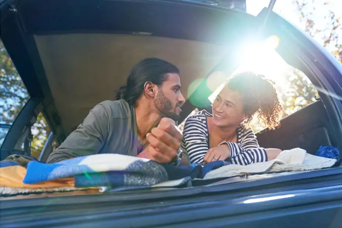 Happy young couple relaxing in back of sunny car