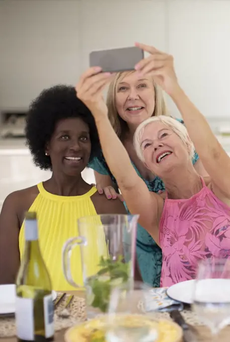 Happy senior women friends taking selfie at lunch