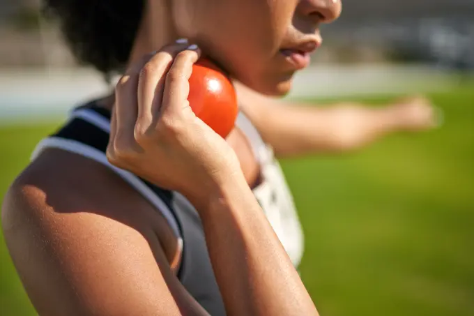 Close up female track and field athlete preparing to throw shot put