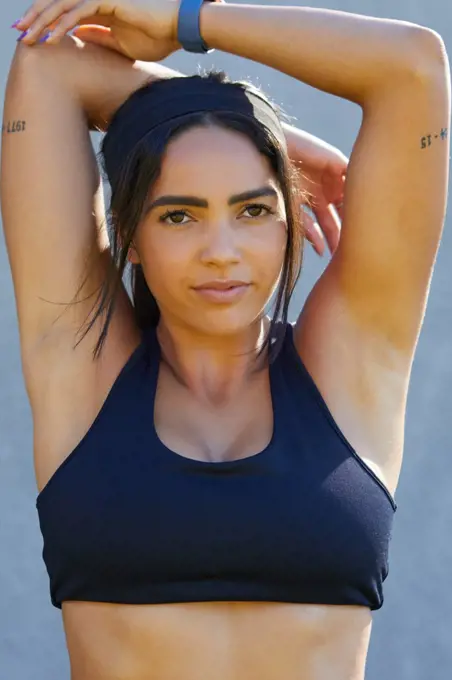 Portrait young female track and field athlete in sports bra stretching