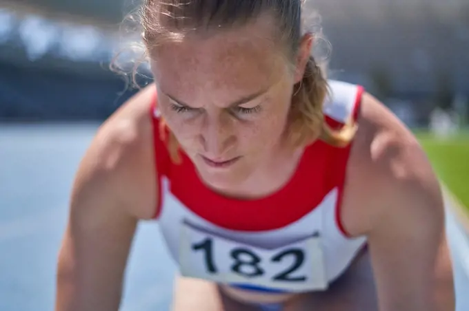 Close up focused female track and field athlete preparing for race