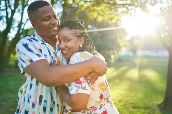 Portrait happy couple hugging in sunny summer park