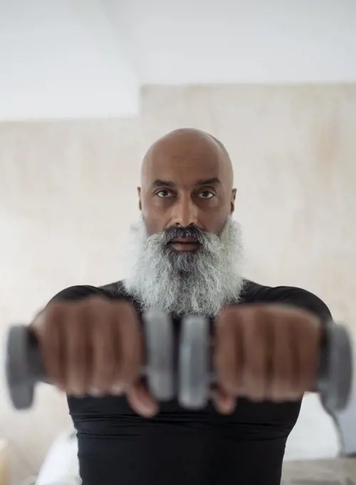 Focused senior man exercising with dumbbells