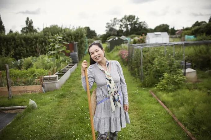 Portrait happy woman gardening in community vegetable garden