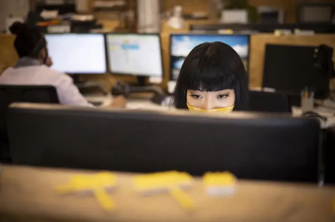 Businesswoman in face mask working at computer in office