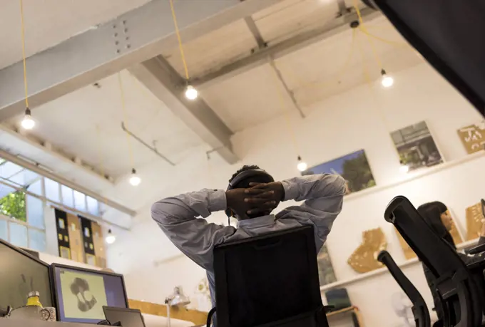 Businessman with hands behind head working in office