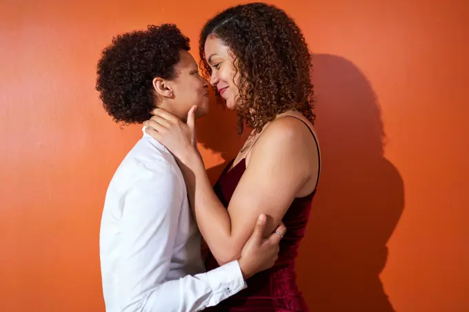 Portrait happy lesbian couple with curly hair smiling face to face