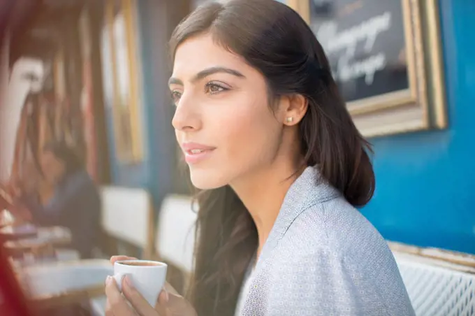 Woman drinking espresso at sidewalk cafe, Paris, France