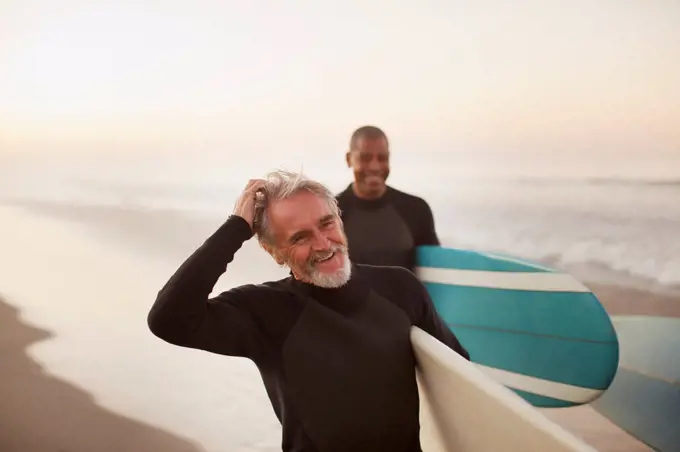 Los Angeles, USA, Older surfers carrying boards on beach