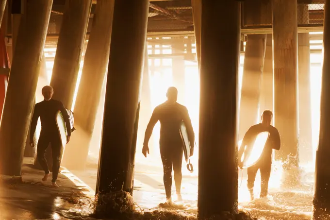 Los Angeles, USA, Surfers carrying boards under pier